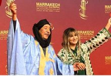 صورة عبد الإله عاجل زوجته يسرقان الأضواء برفع العلم المغربي على السجادة الحمراء